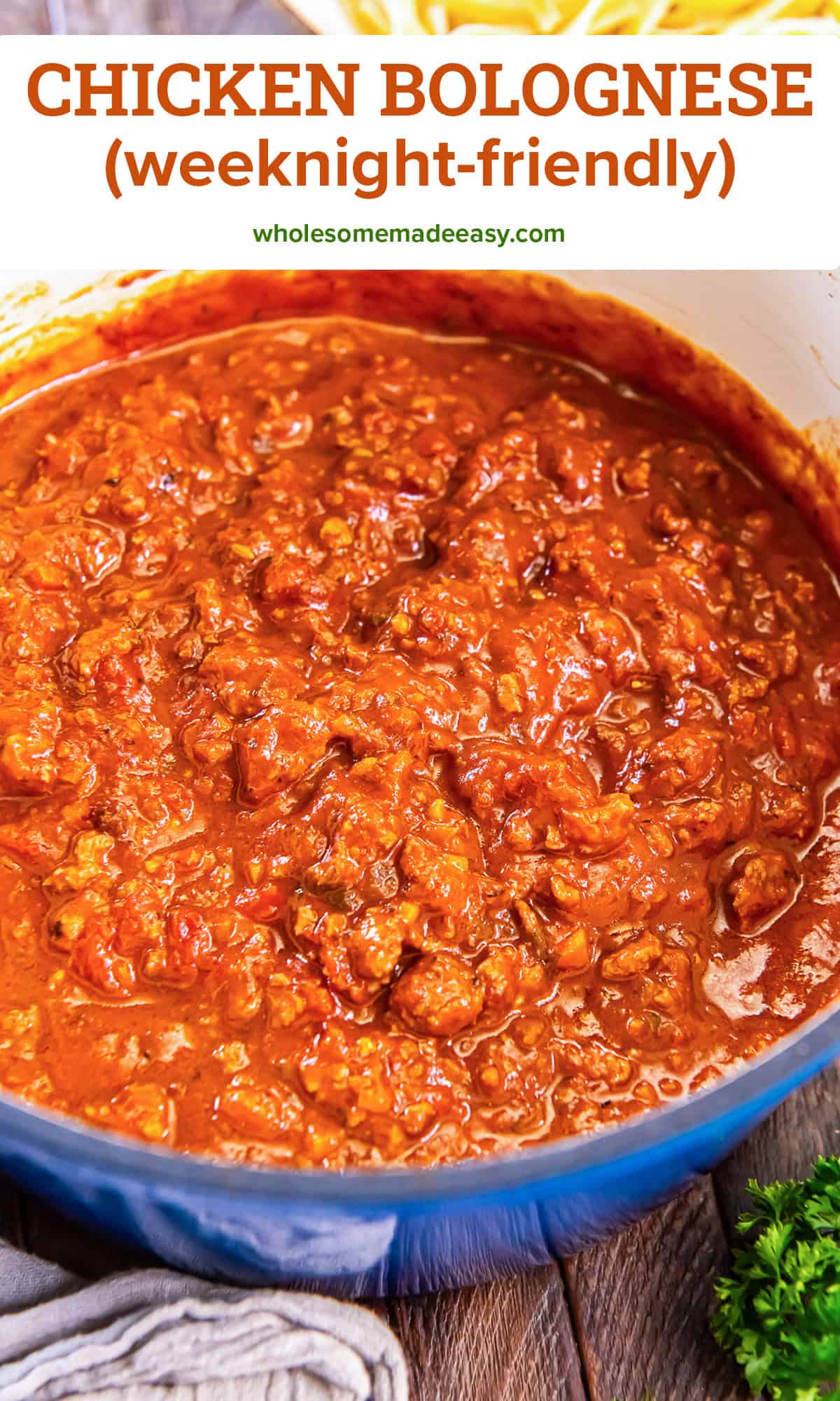 Chicken Bolognese in a blue Dutch oven, rich tomato sauce with ground chicken and vegetables with text overlay.