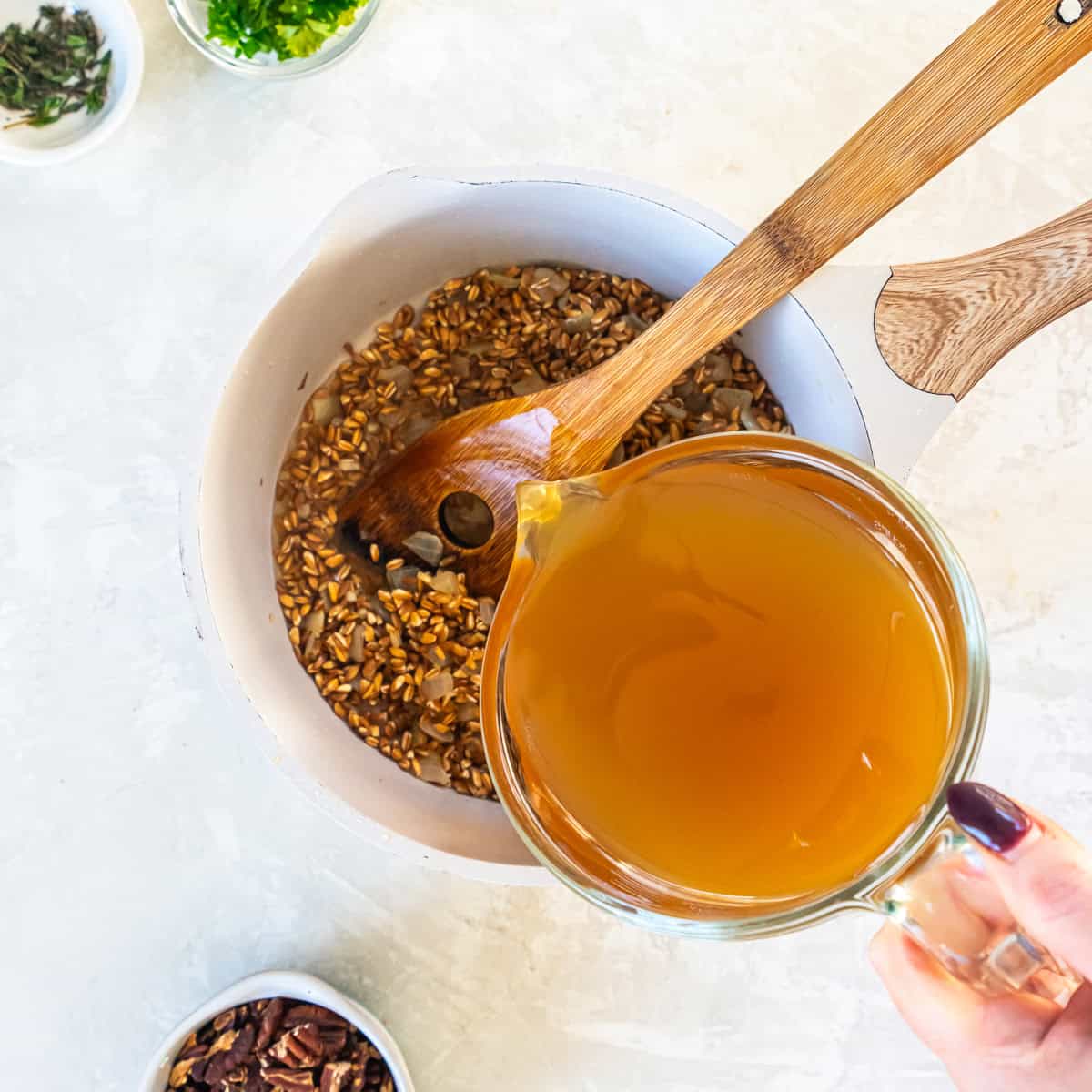 Broth is added to the saucepan with the farro.
