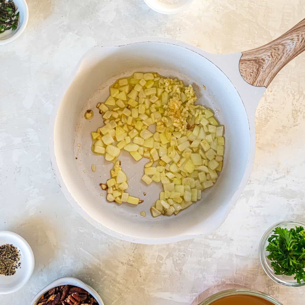 Onions cooking in a white saucepan.