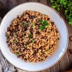 Warm farro pilaf mixed with toasted nuts and herbs, garnished with parsley.