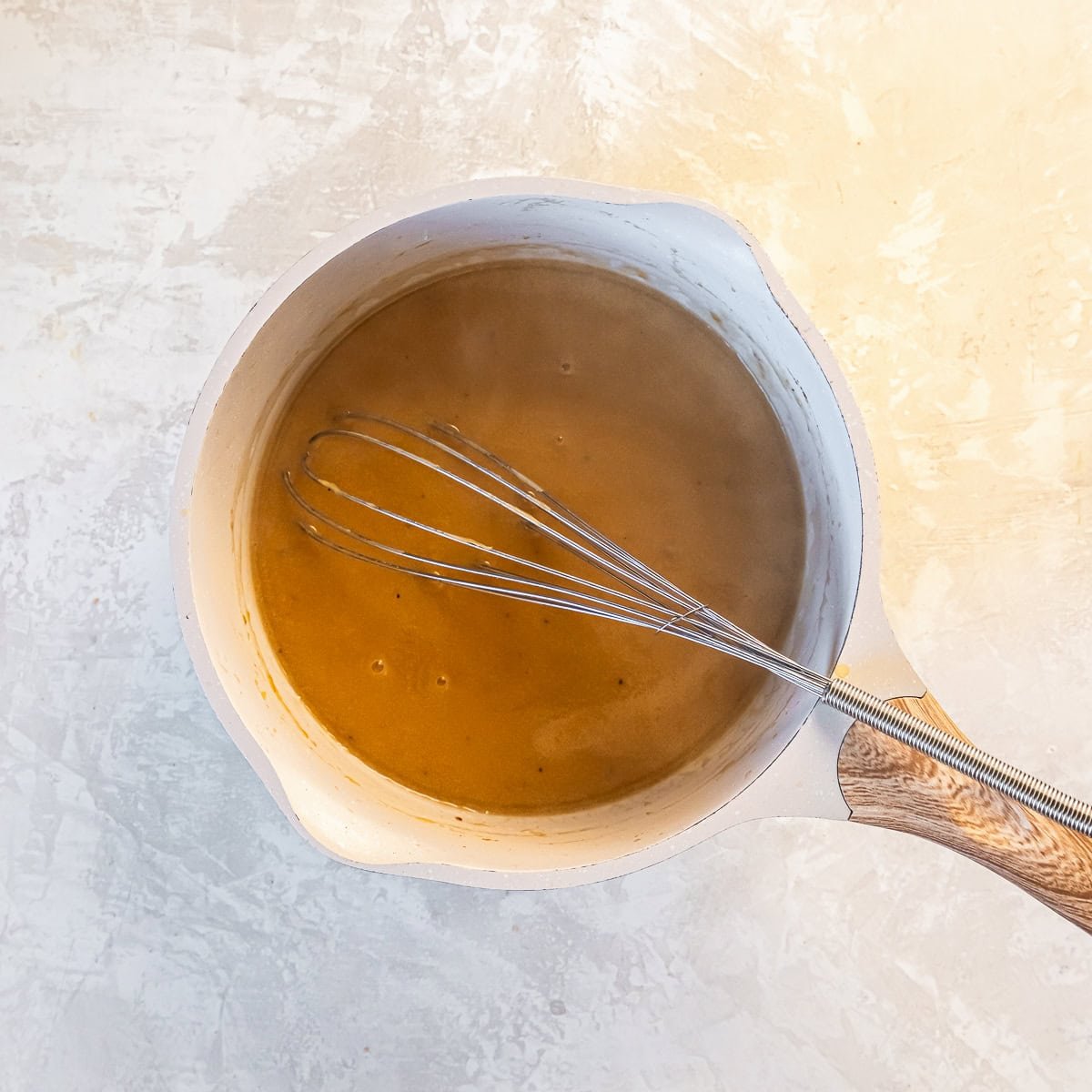 Whisking turkey gravy in a saucepan to thicken.