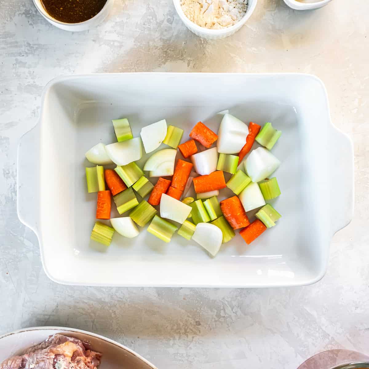Chopped onion, carrots, and celery arranged in the bottom of a baking dish to create a roasting bed for turkey.