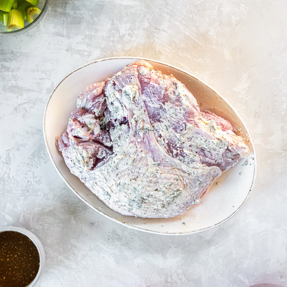 Bone-in turkey breast fully coated with herb butter mixture before roasting.