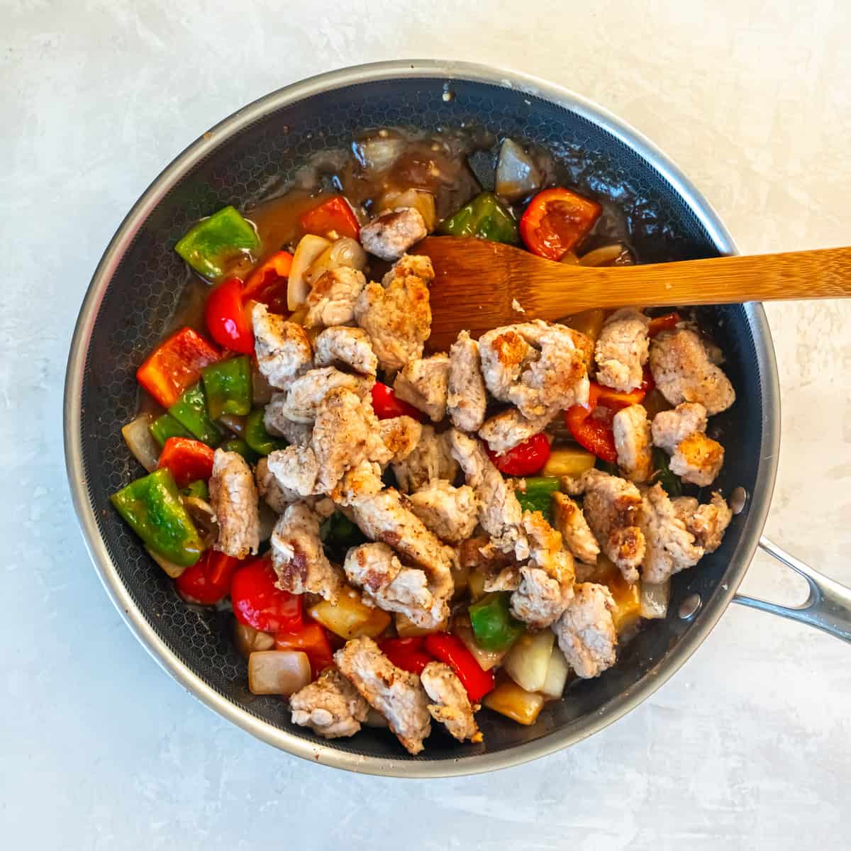 Cooked pork tenderloin added back to the skillet with vegetables and sweet and sour sauce.