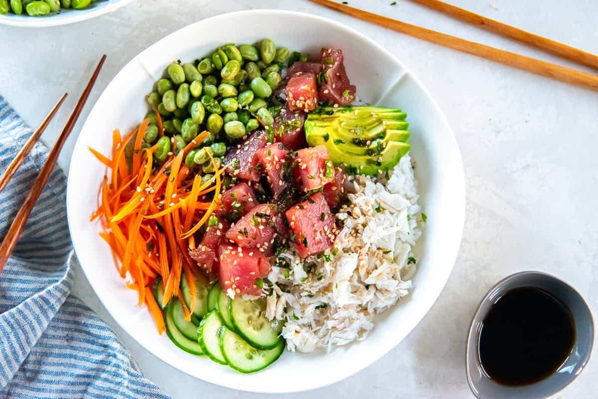 Ahi tuna poke bowl with marinated tuna, crab meat, avocado, cucumber, shredded carrot, and edamame served over white rice.
