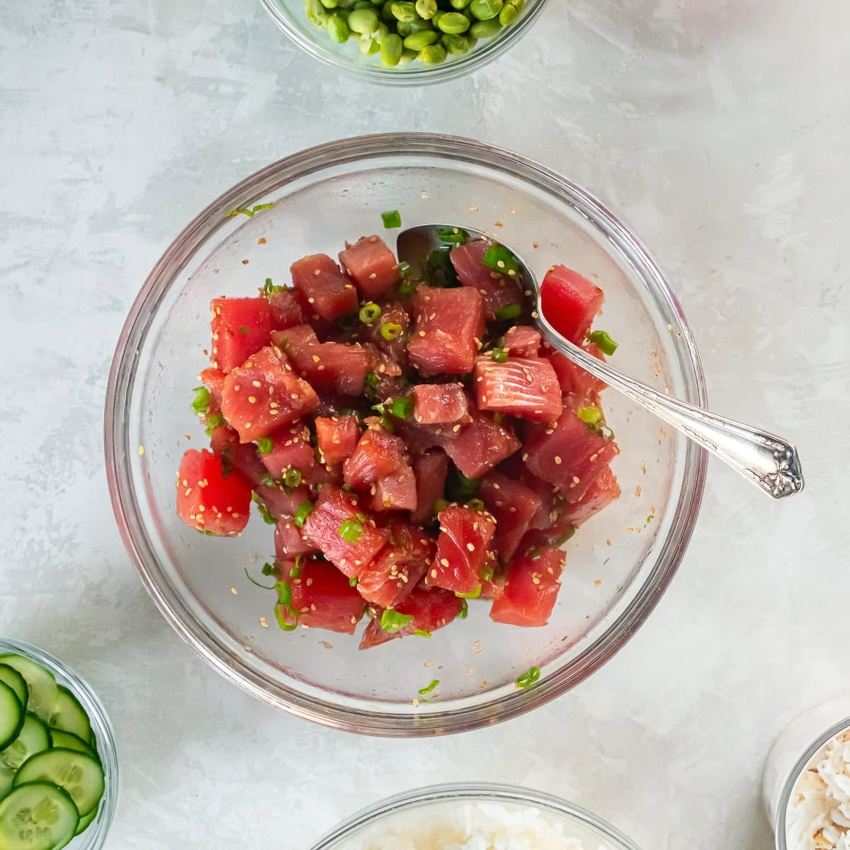 Cubed ahi tuna tossed with soy sauce, mirin, sesame oil, green onions, and sesame seeds in a bowl.