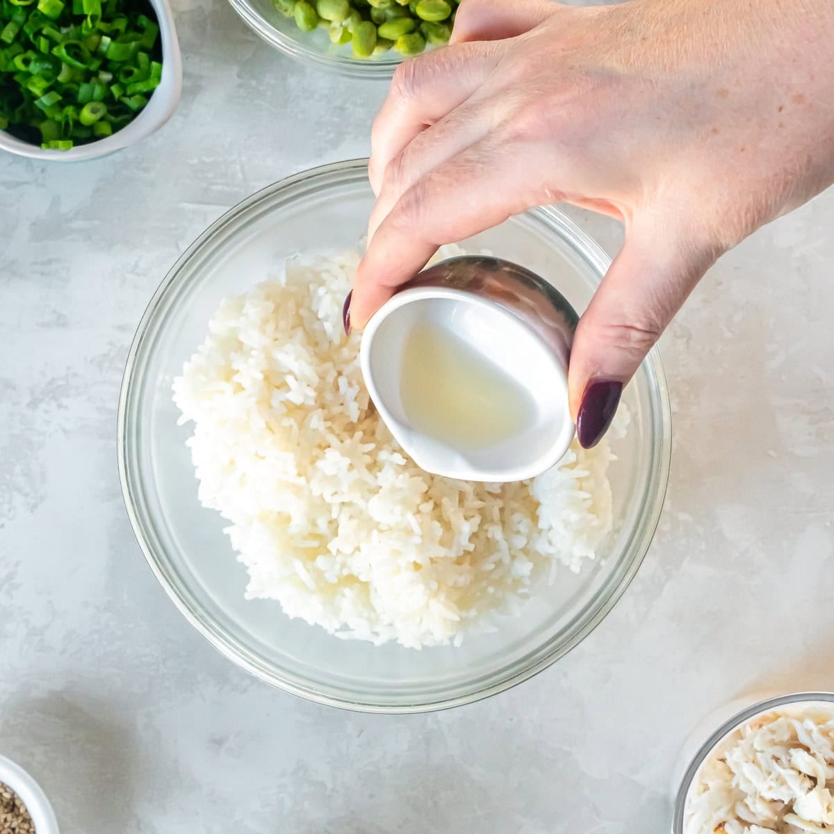 Adding seasoned rice vinegar to freshly cooked white rice for ahi tuna poke bowls.