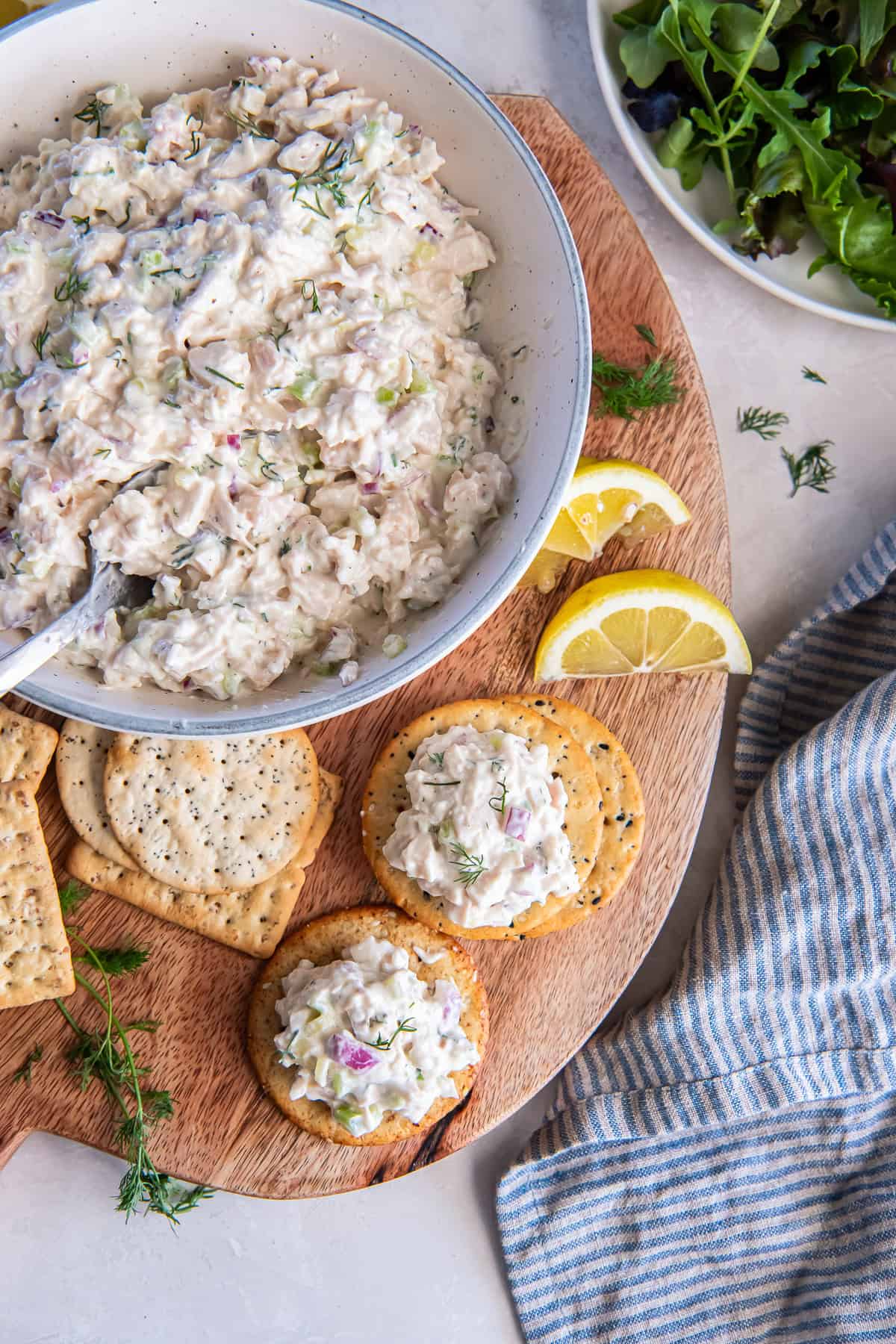Cottage cheese chicken salad served on round crackers on a wooden board.