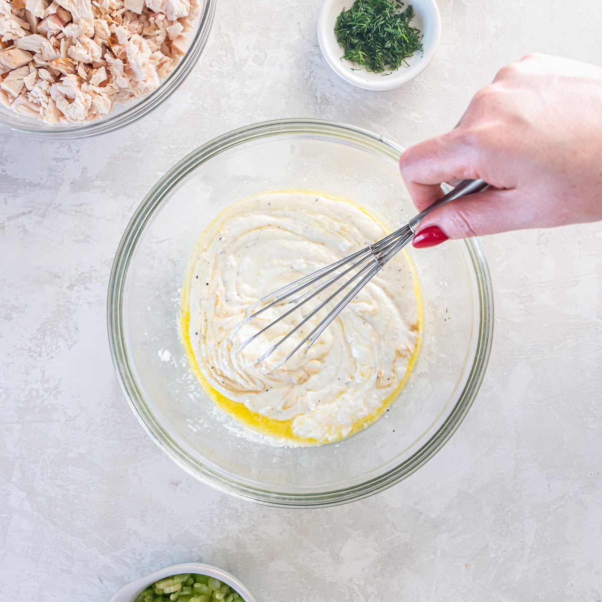 A whisk combining blended cottage cheese with oil and lemon juice in a bowl.