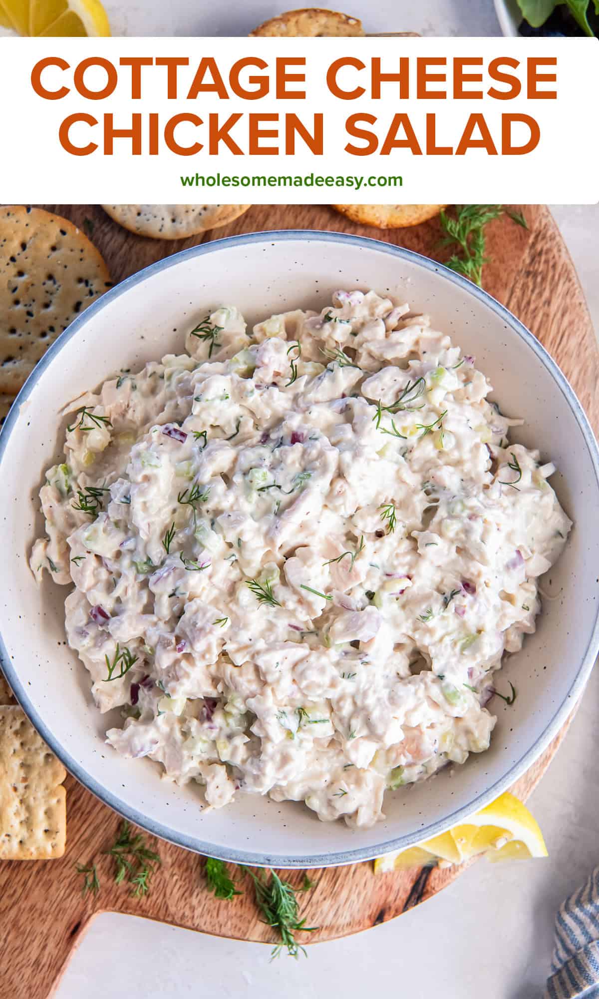 A bowl of cottage cheese chicken salad in a bowl with crackers, lemon wedges, and fresh dill with title text overlay.