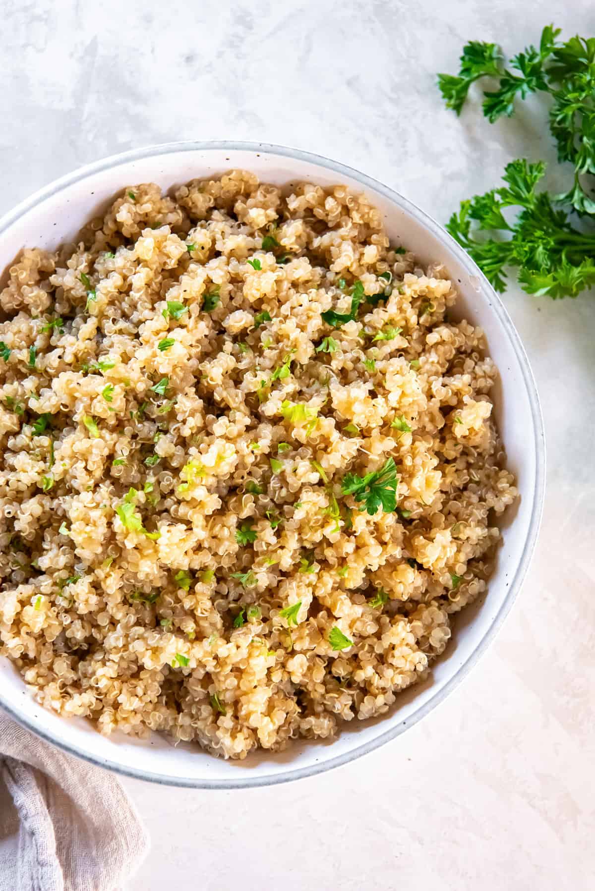Garlic butter quinoa cooked in broth and garnished with fresh parsley in a white bowl.