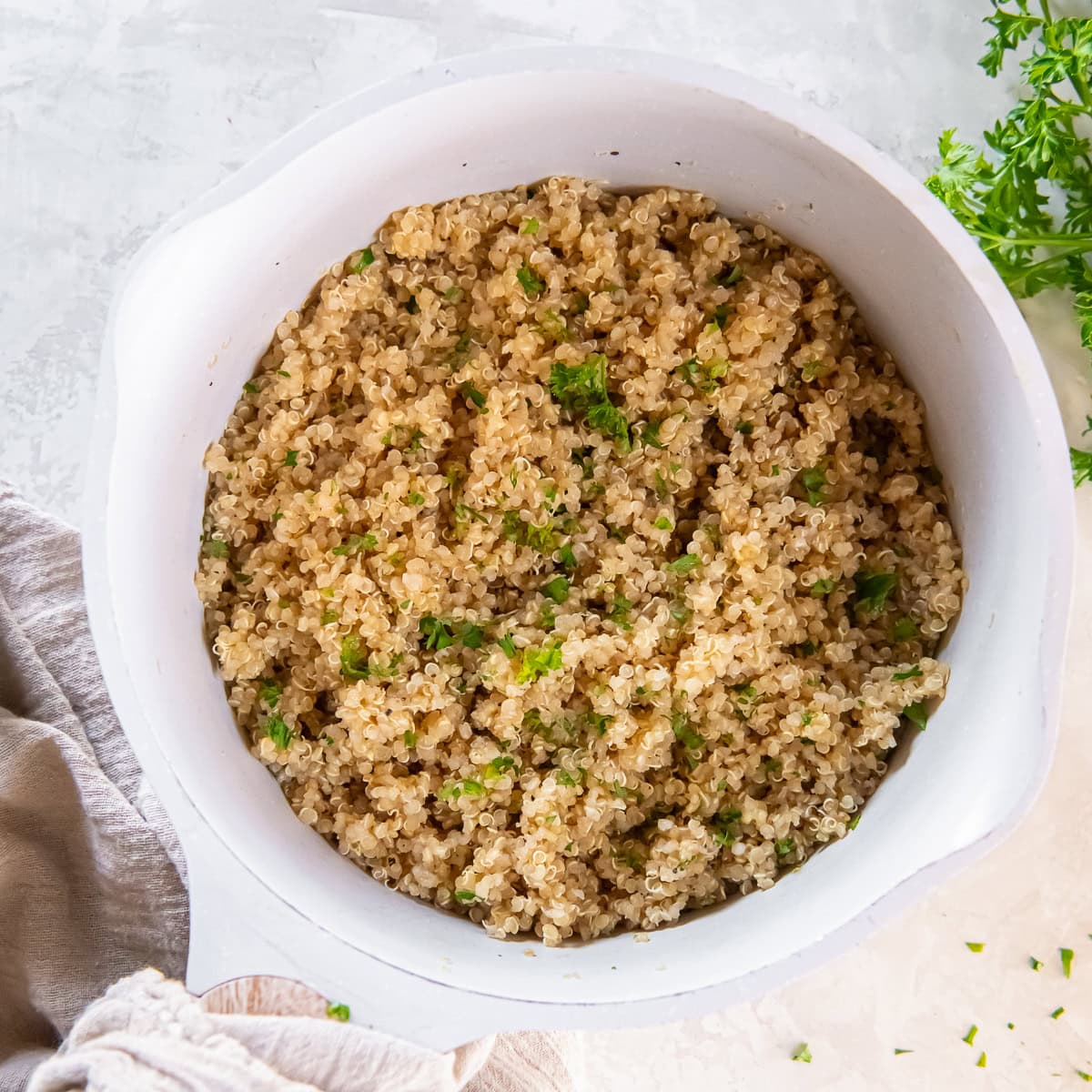 Cooked quinoa fluffed with fresh herbs in a saucepan.