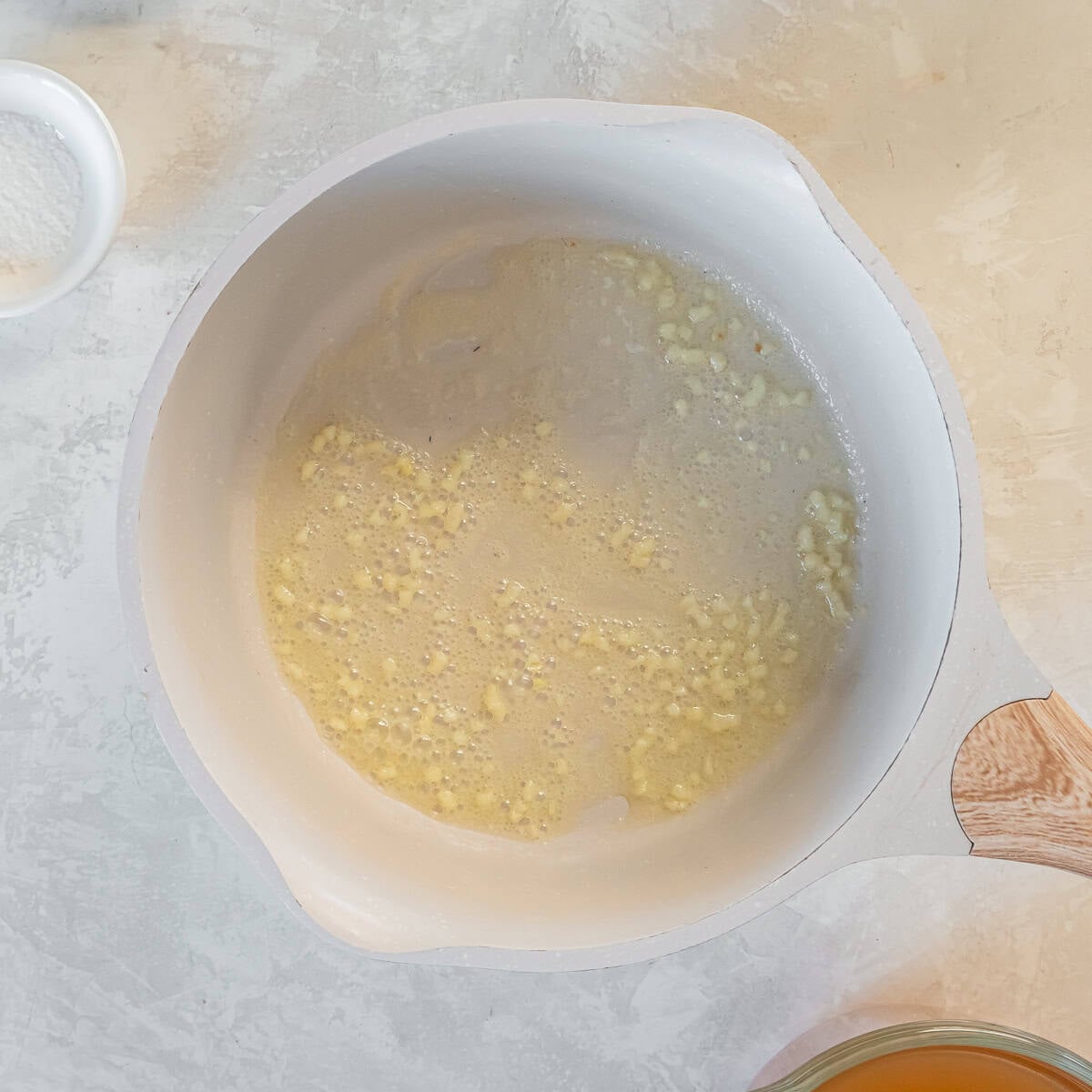 Melted butter with minced garlic cooking in a saucepan until fragrant.
