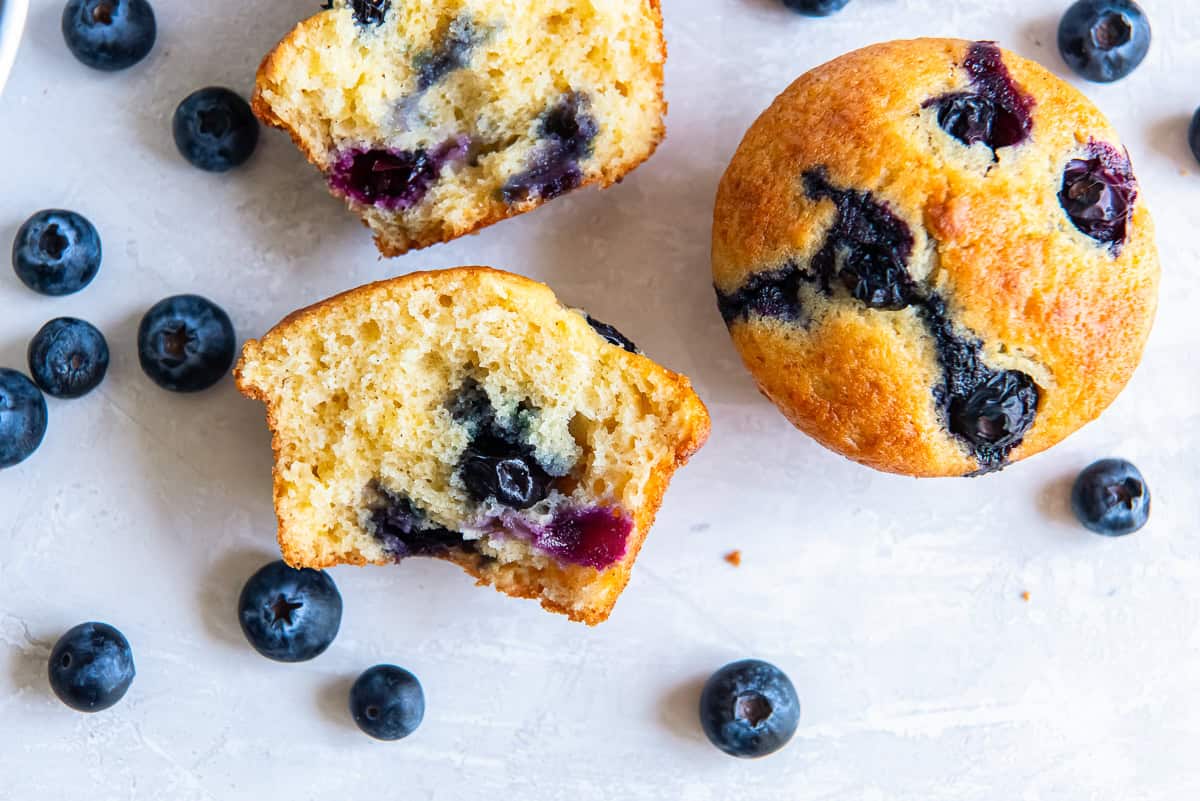 Split non-dairy blueberry muffins made with silken tofu, revealing a tender crumb and blueberries.