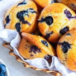 Blueberry muffins made with silken tofu with golden tops and juicy blueberries in a basket.