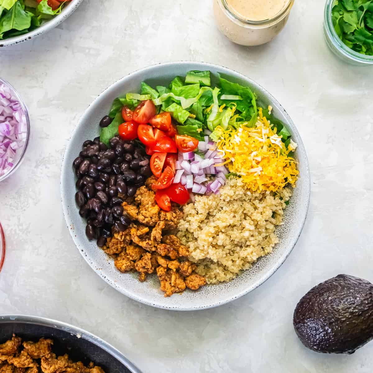 Chicken Taco Grain Bowl topped with romaine, quinoa, seasoned chicken, black beans, tomatoes, red onion, and shredded cheddar cheese.