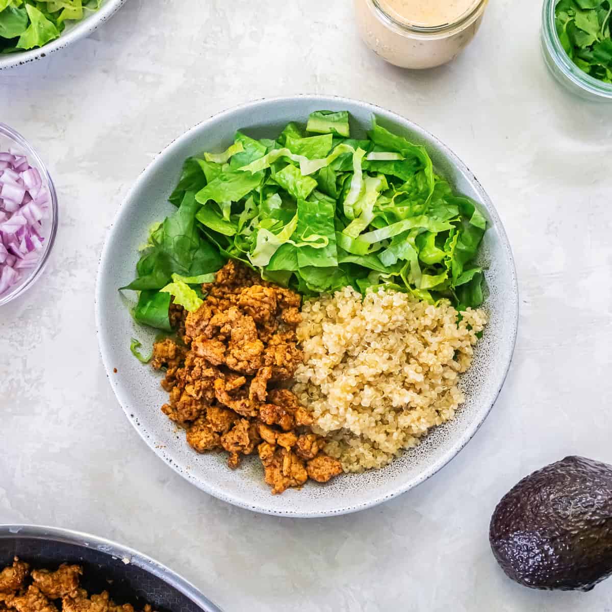 Chicken Taco Grain Bowl with romaine, seasoned ground chicken, and quinoa arranged in a bowl with cilantro lime dressing and fresh ingredients nearby.