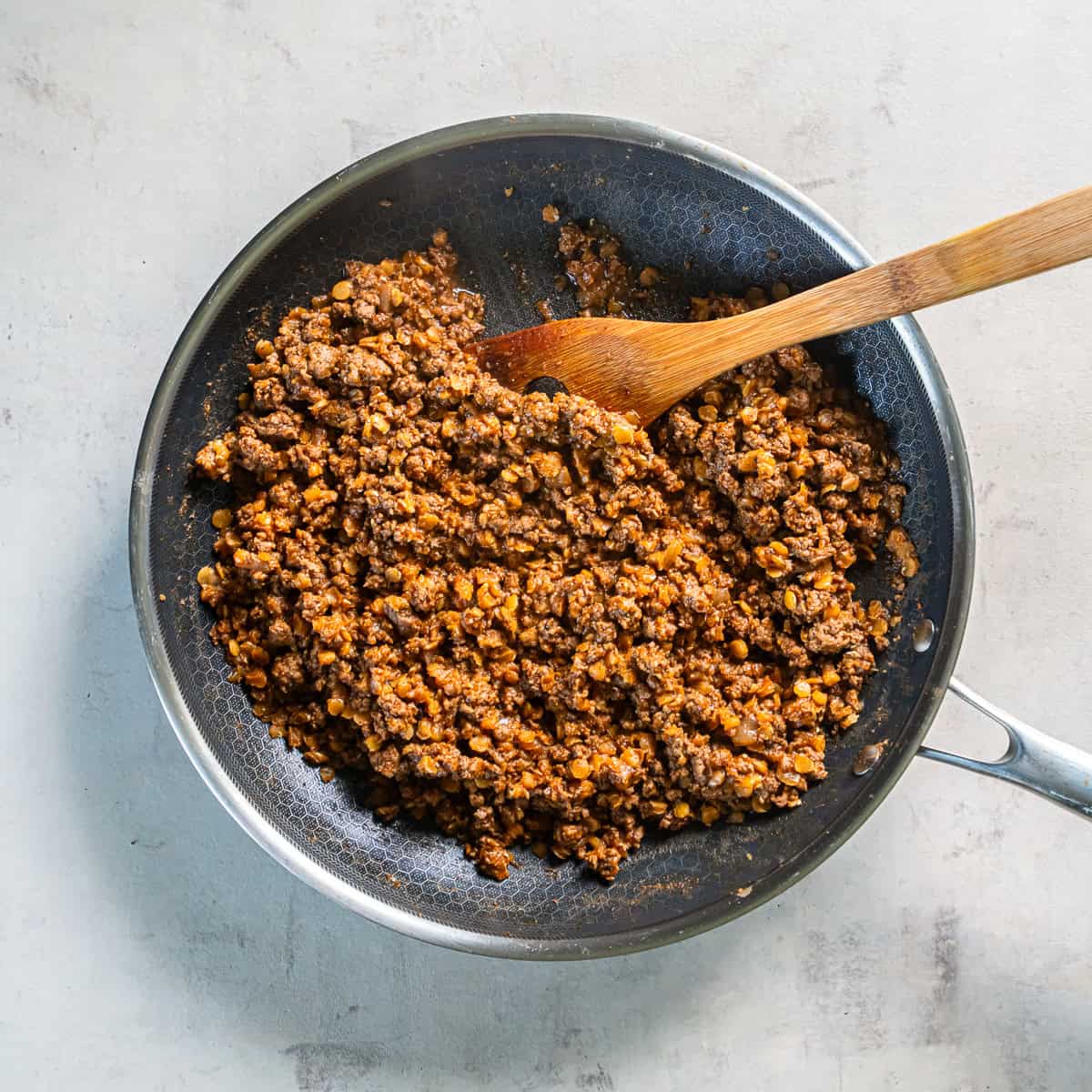 Taco seasoning and tomato paste added to browned ground beef and onion in a skillet.