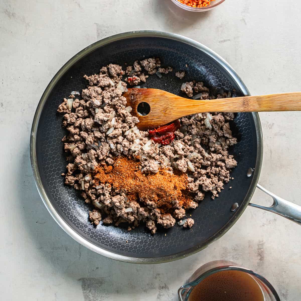 Taco seasoning and tomato paste added to browned ground beef and onion in a skillet.