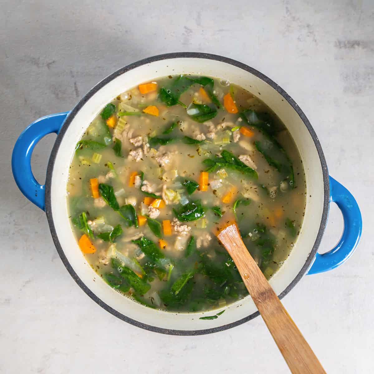 Finished Turkey White Bean Soup with ground turkey, cannellini beans, spinach, carrots, and celery in a Dutch oven.