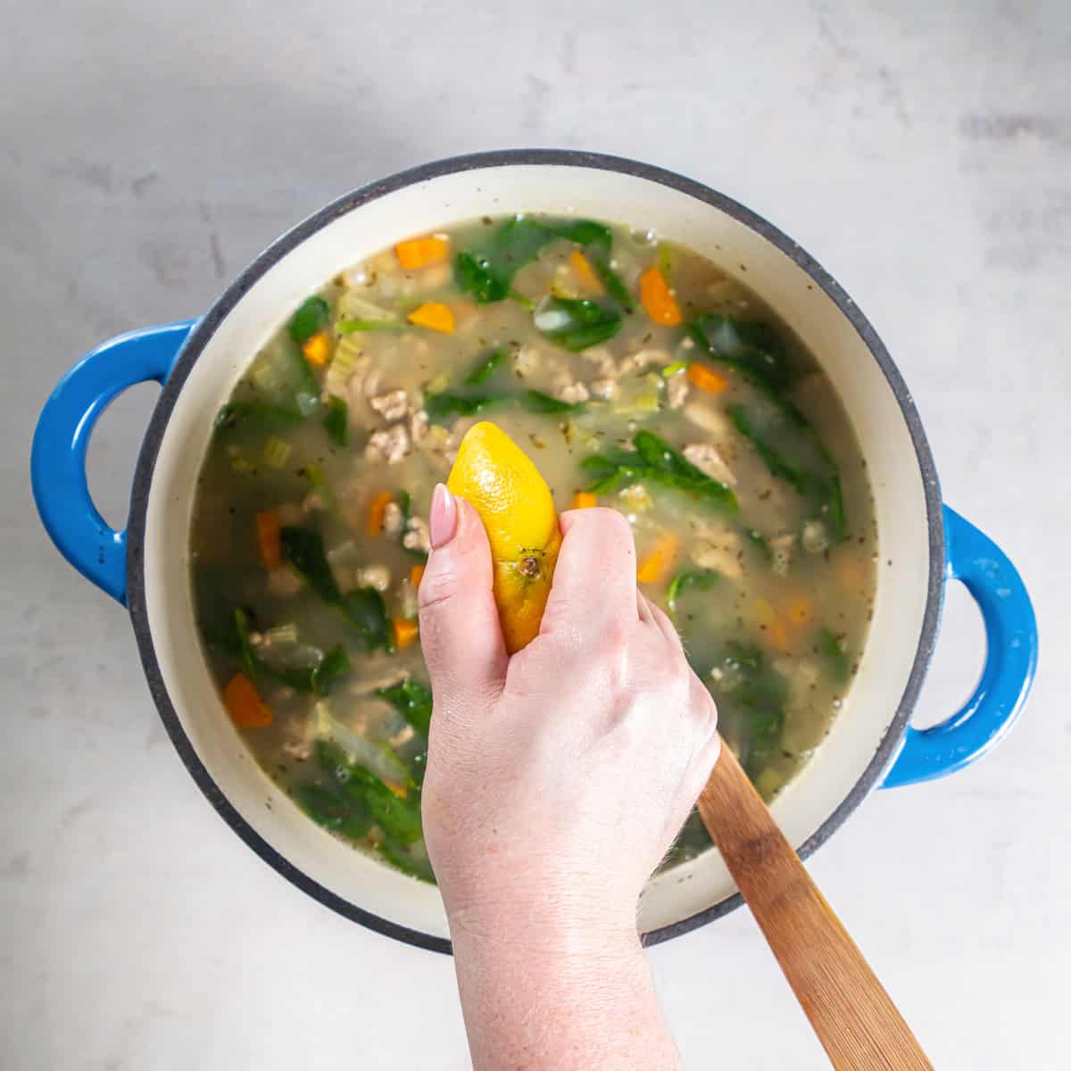 Fresh lemon juice being squeezed into the finished turkey white bean soup.