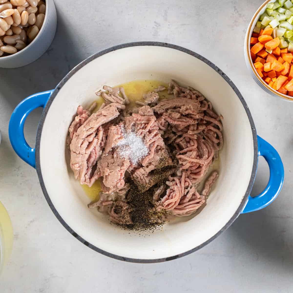 Ground turkey seasoned with salt and pepper cooking in olive oil in a Dutch oven.