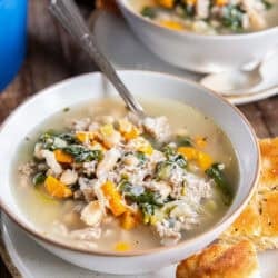 Bowl of Turkey White Bean Soup with ground turkey, cannellini beans, spinach, carrots, and Parmesan, served with crusty bread.